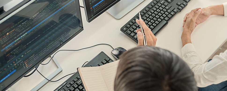 Person analyzing code on a computer screen with a keyboard nearby.