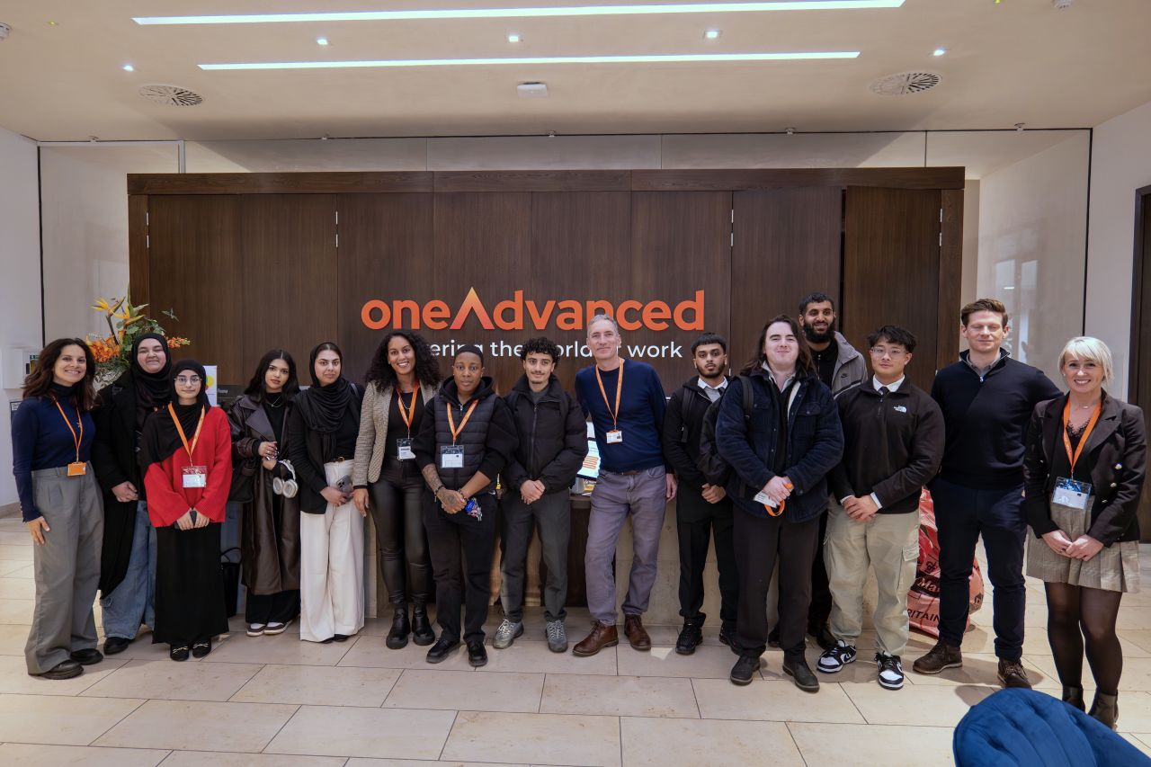 a group standing and smiling in front an oneAdvanced wall
