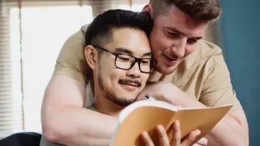 Two people embracing while looking at a notebook.