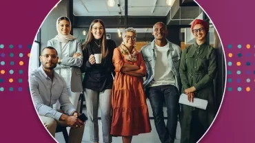 Group of six people smiling in a modern office setting.