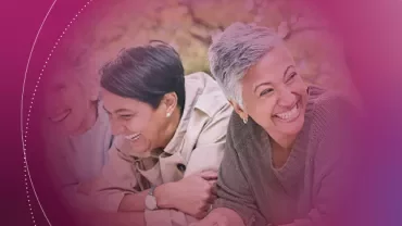 Three people laughing together outdoors with a warm, soft pink overlay.