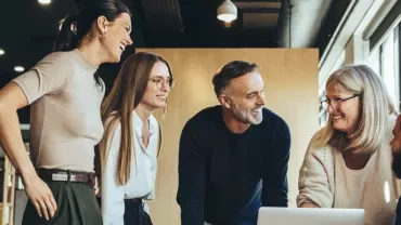 Group of people smiling and discussing in a modern office.