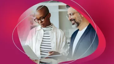 Two people smiling and looking at a laptop together.