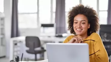 a girl smiling sitting in an office with a white computer