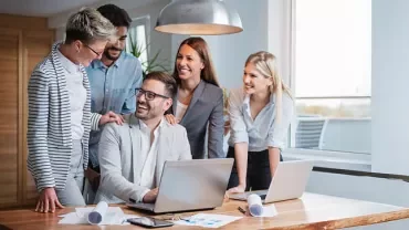 a group of people smiling and working together in an office