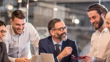 a group of people laughing and talking in the office