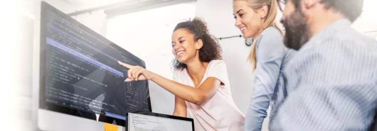 Group collaborating on code project at computers in office.