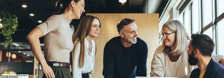 Group of people smiling and discussing in a modern office.