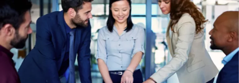 Group of people discussing around a laptop in an office setting.