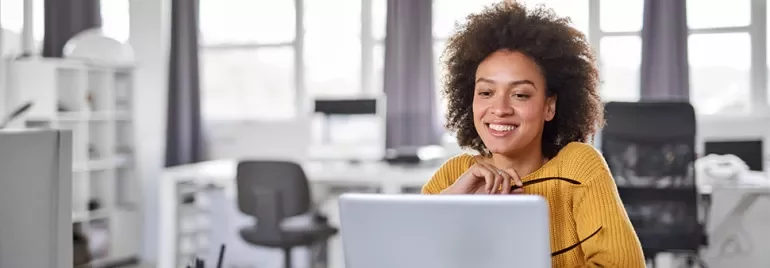 a girl smiling sitting in an office with a white computer