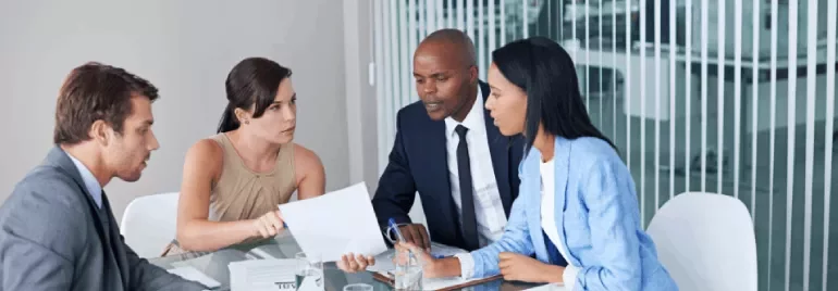 A group of colleagues talking and pointing at a report in an office