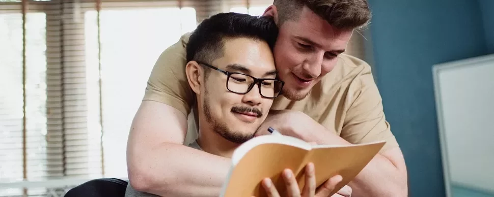 Two people embracing while looking at a notebook.
