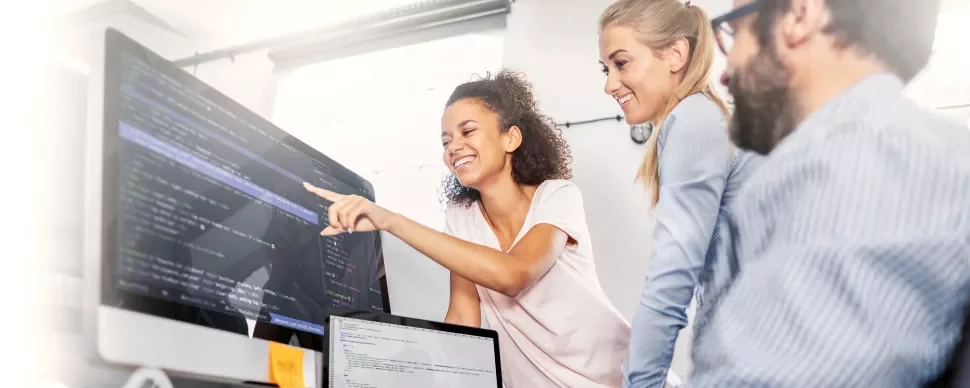 Group collaborating on code project at computers in office.