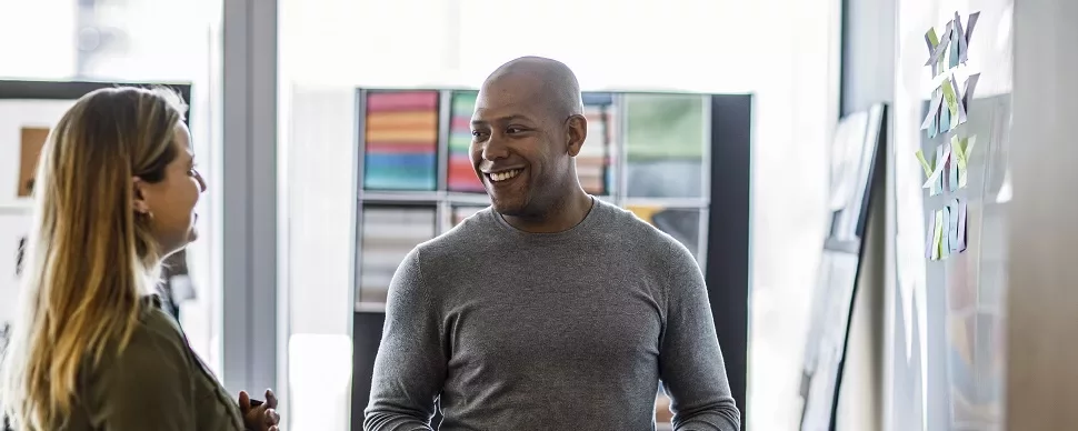 Two people smiling and chatting in an office environment.