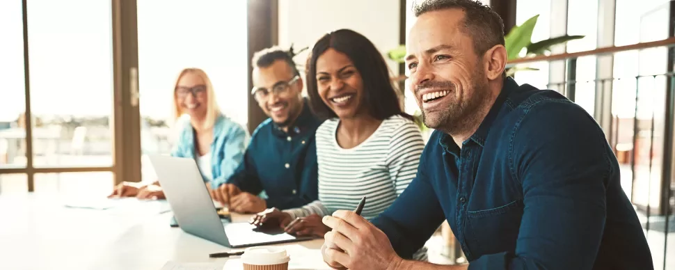 Group of people smiling and sitting at a conference table.