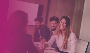 People in a meeting, one shaking hands, smiling.