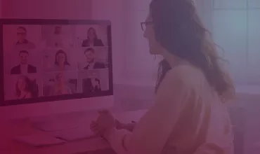 Person participating in a virtual meeting with a group of people displayed on a monitor.