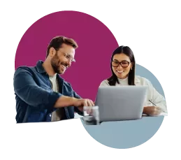 Two people working together on a laptop, smiling.